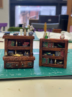 Dos librerías de madera en miniatura con libros, cajones y recipientes decorativos
