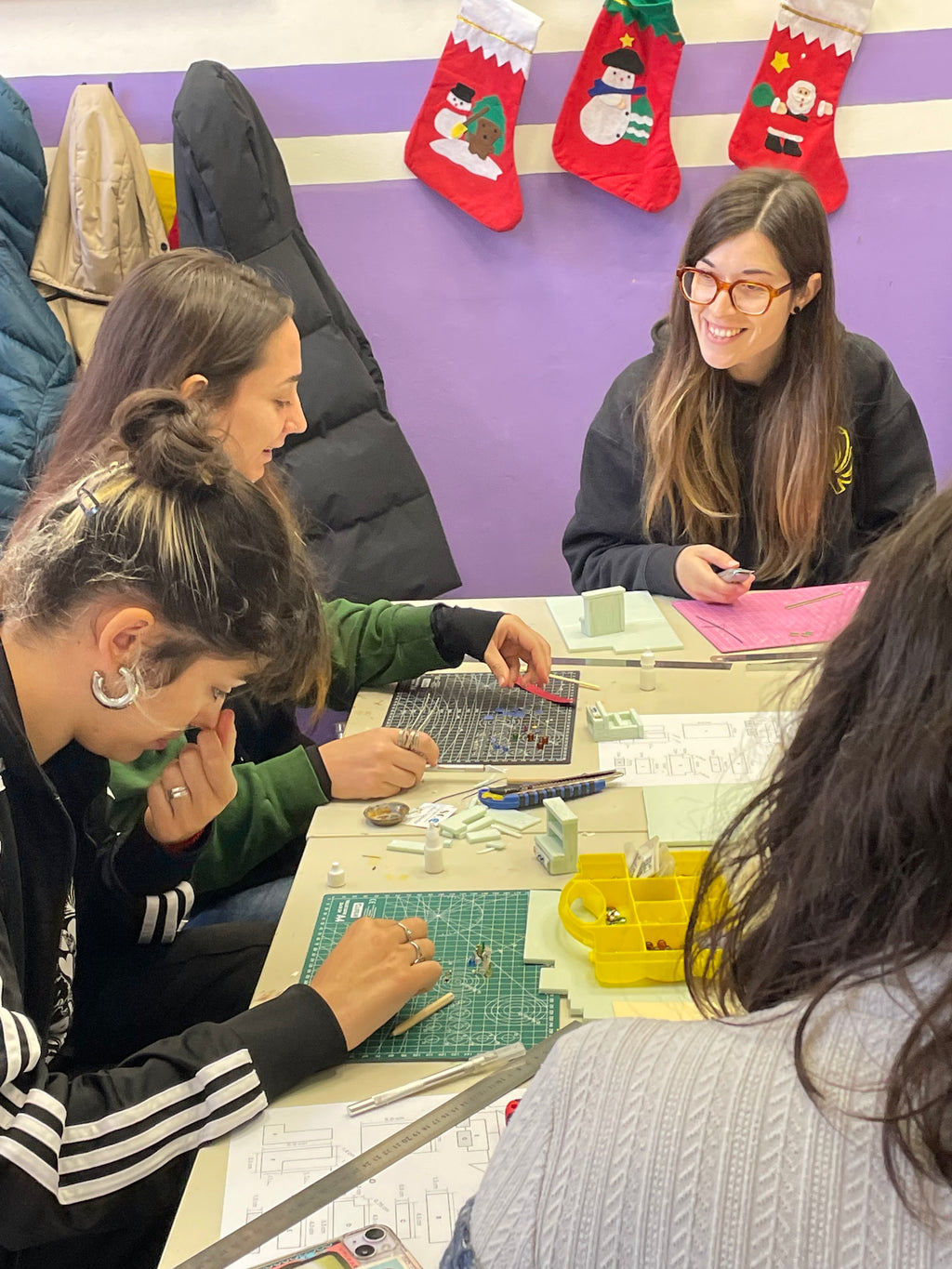 Participantes construyendo mobiliario en miniatura alrededor de una mesa del taller