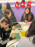 Participantes construyendo mobiliario en miniatura alrededor de una mesa del taller
