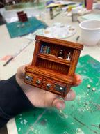 Librería marrón en miniatura con libros y tiradores de cajón, sostenida con la mano